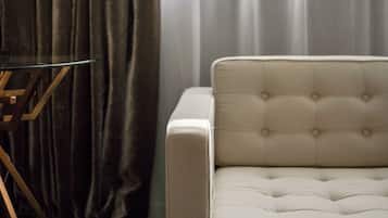 A room with a sofa, a lamp on a stand, and a window with curtains.