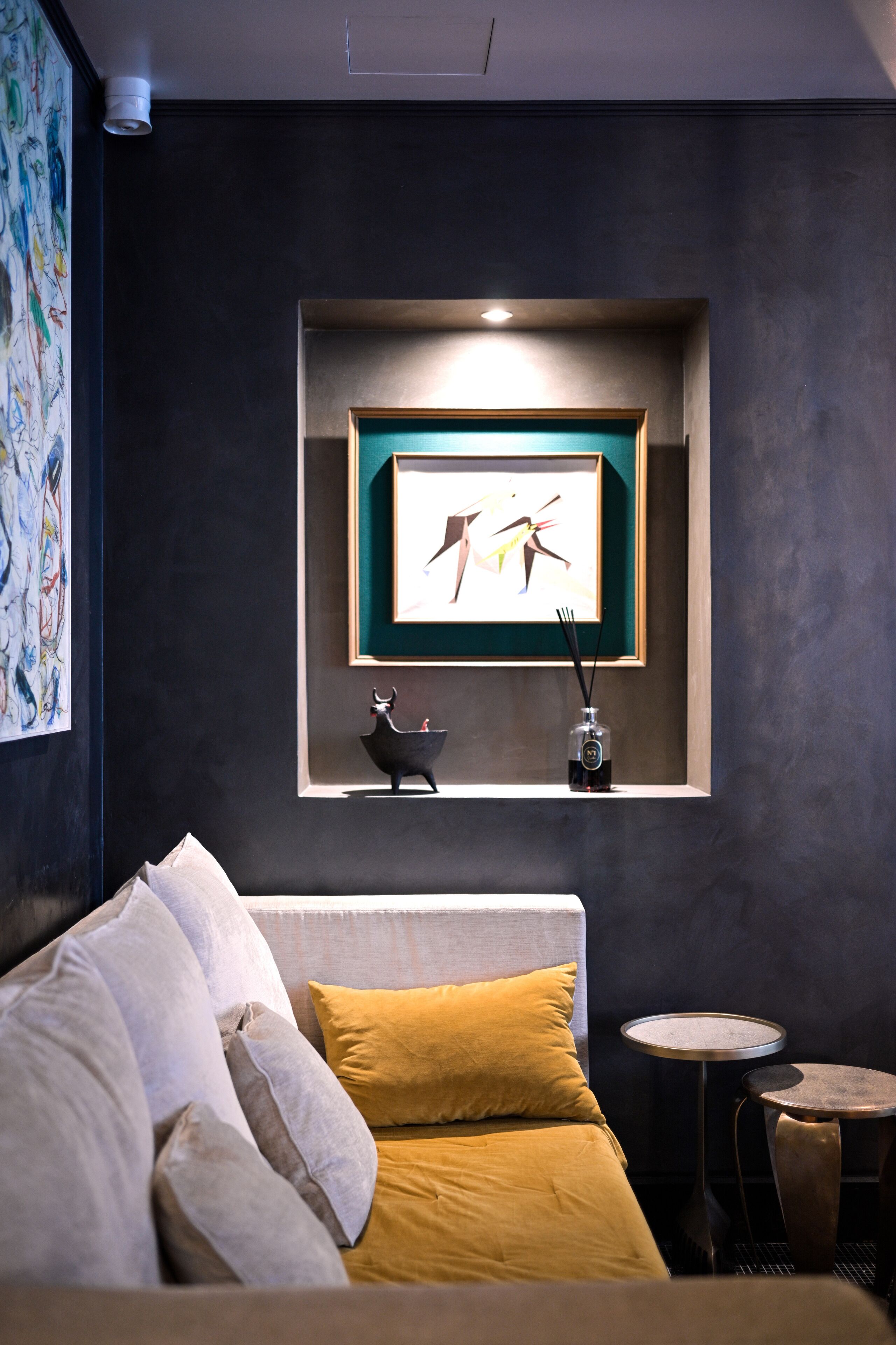 A modern room with a bed, a small table, and a framed artwork on the wall.
