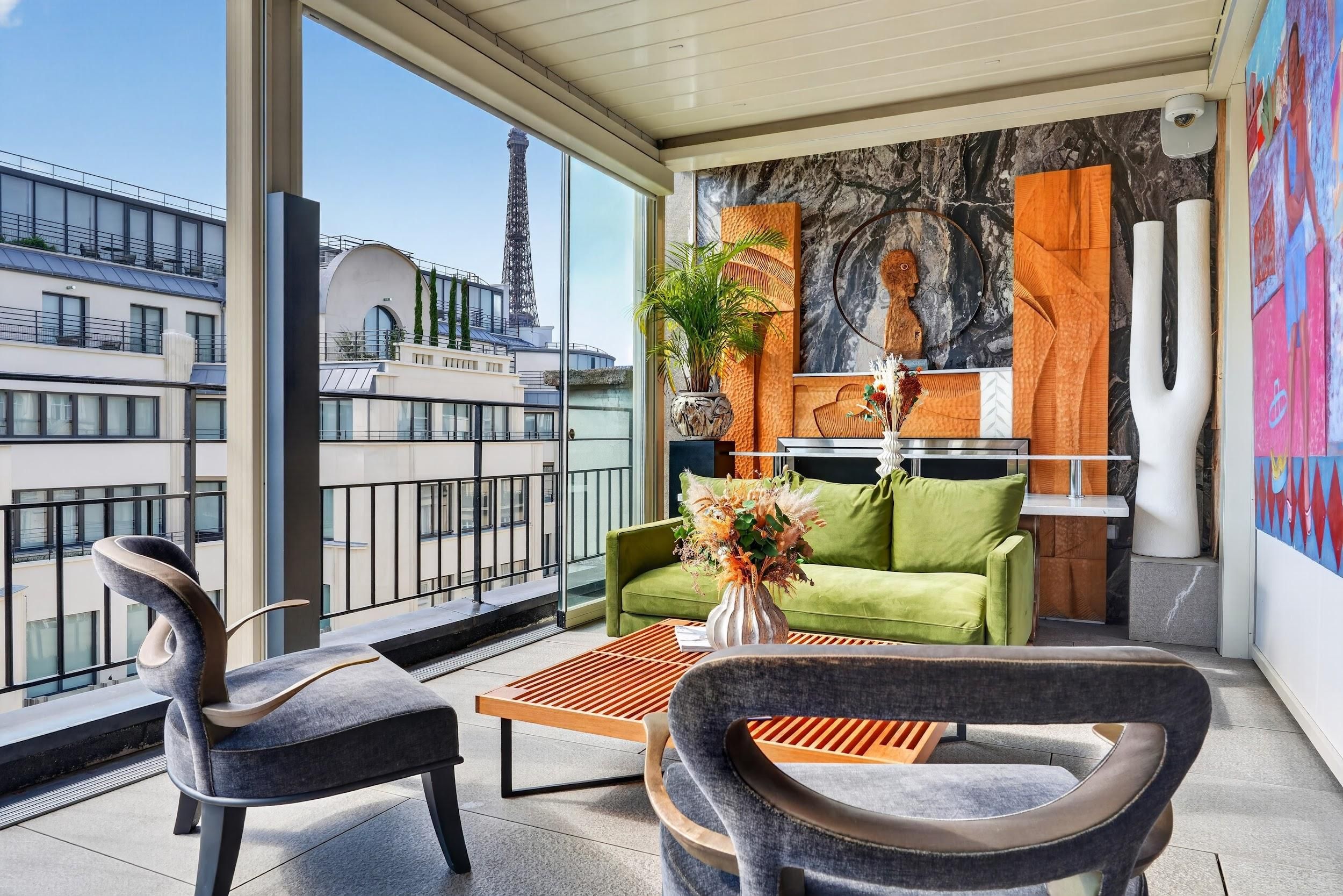 Uma sala de estar moderna com sofá, cadeiras, mesa de centro e vista para a Torre Eiffel.