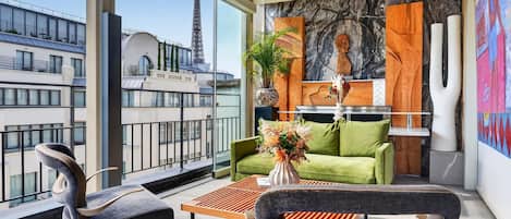 A modern living room with a sofa, chairs, a coffee table, and a view of the Eiffel Tower.