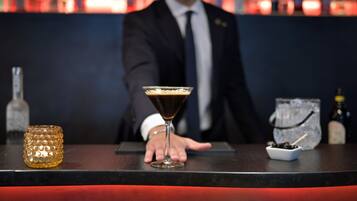 Un bar avec un barman, un verre à martini, un petit bol d’olives et une bouteille de spiritueux.