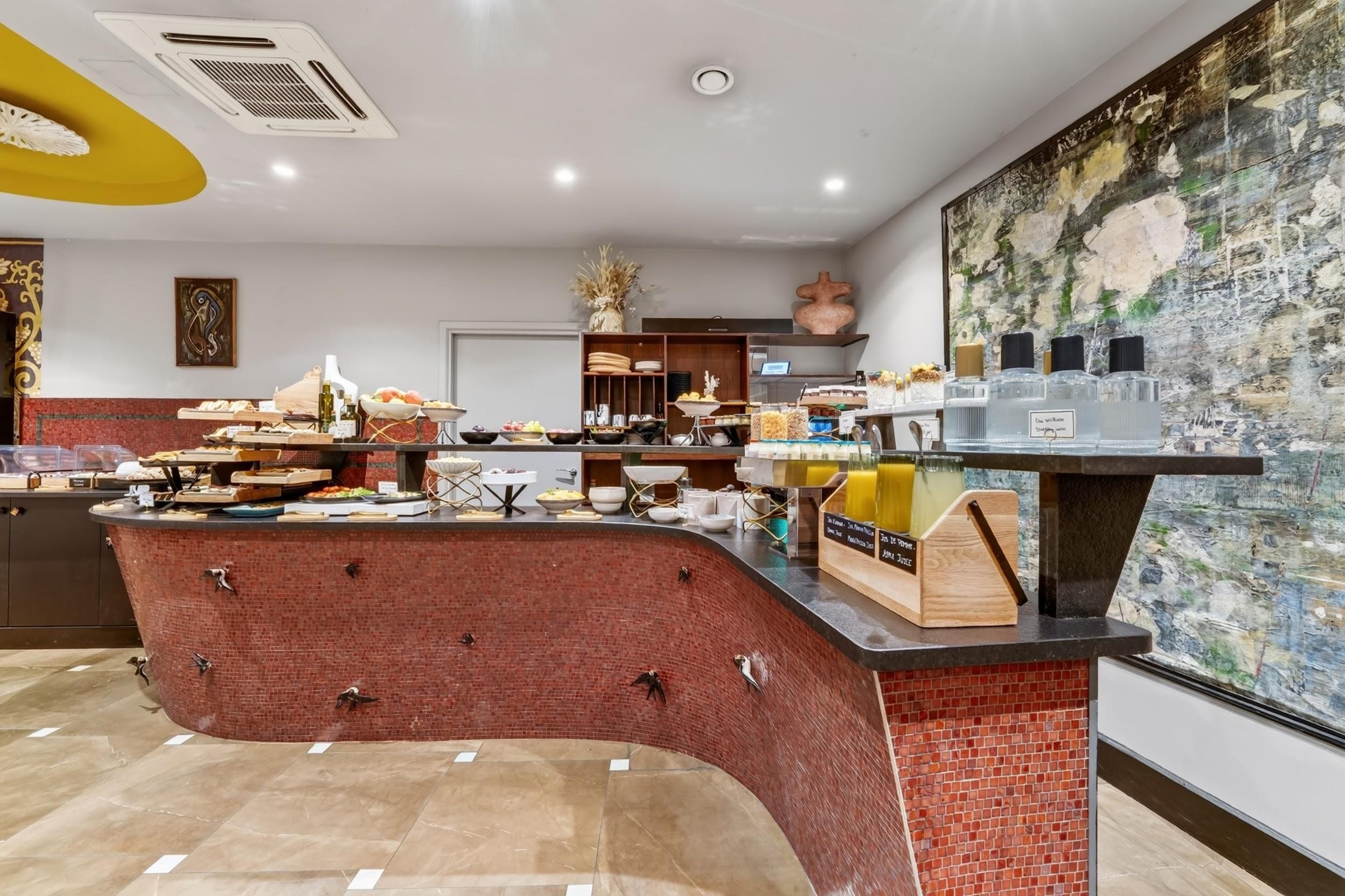 Una cocina moderna con una barra curva de ladrillo, diferentes puestos de comida y un mural en la pared.