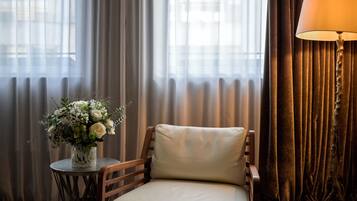 Una habitación con una silla, una mesita con un florero y una lámpara.