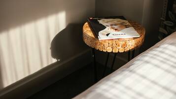 Un tabouret rond en bois, sur lequel est posé un livre intitulé « Cinéma », placé près d’une fenêtre munie de stores.