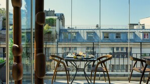 A balcony with a table set for breakfast, overlooking a residential area with buildings and a clear sky. - The One Alma Paris (Paris)