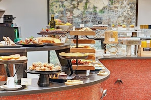 A buffet with various food items and a brick wall in the background. - The One Alma Paris (Paris)