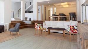 Amplia sala de estar con sofá, sillas y una escalera que sube a otro nivel.