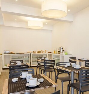 Een moderne eetruimte met tafels, stoelen, een koffiehoek en een toonbank met etenswaren.