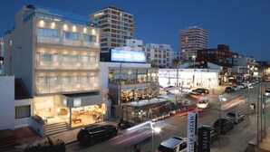 Un hotel moderno con fachada de vidrio, varios pisos y un restaurante visible en la planta baja.