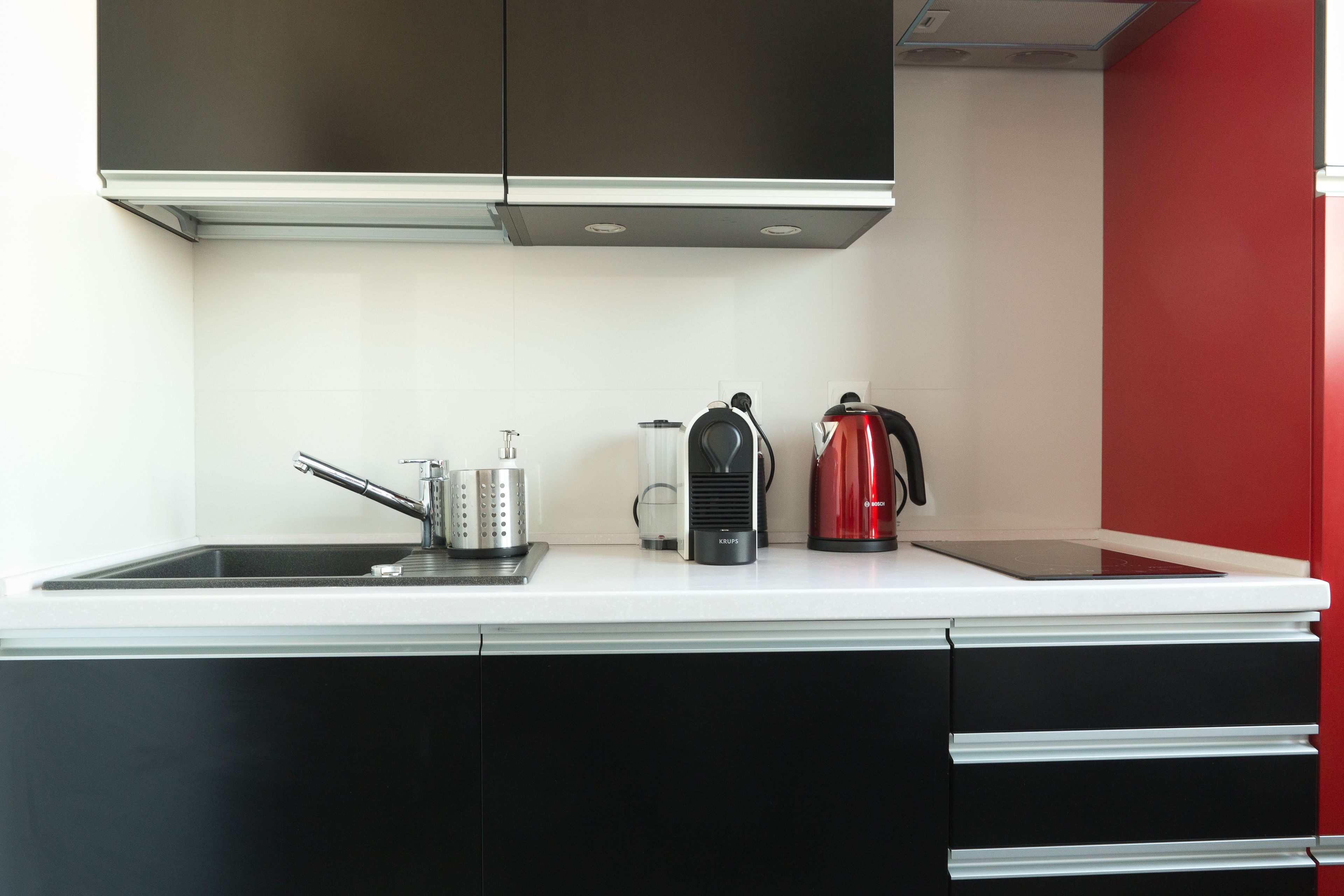 Een moderne keuken met een zwart-wit aanrecht, een waterkoker, een koffiezetapparaat en een rasp.