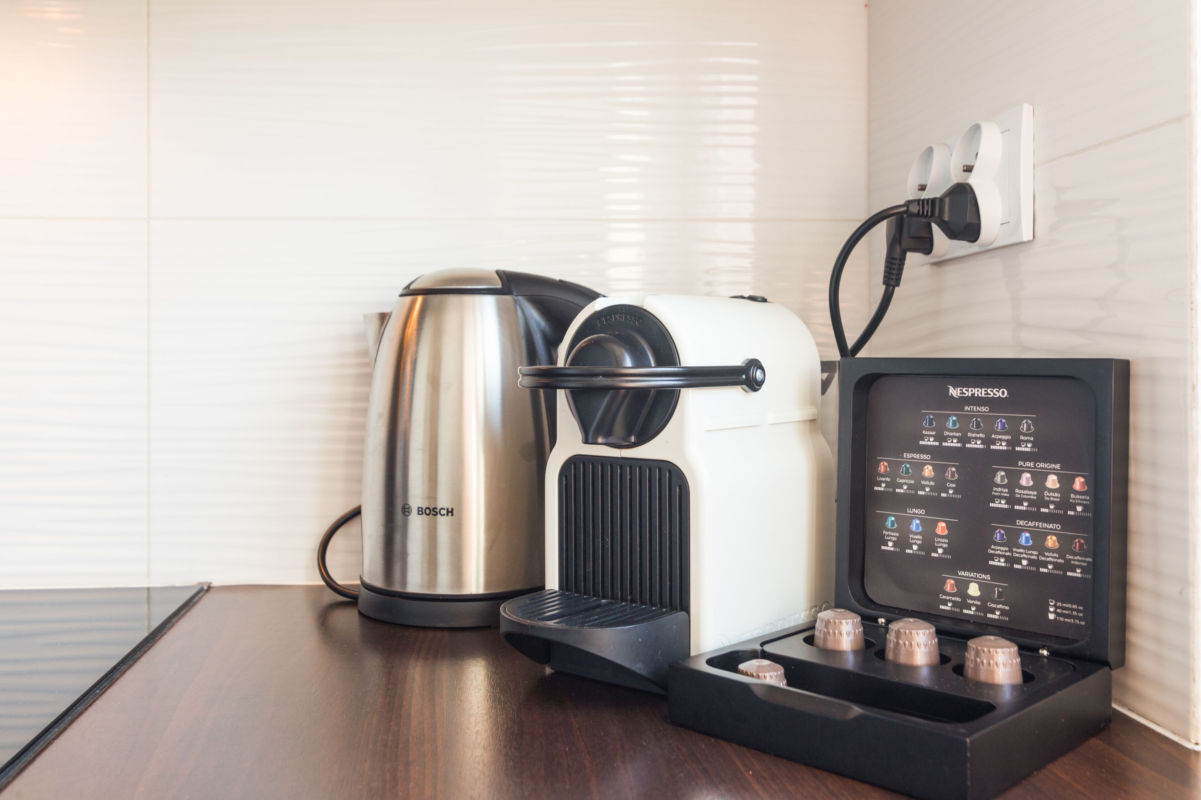 A coffee machine with a coffee pod holder and a Bosch kettle on a wooden table.