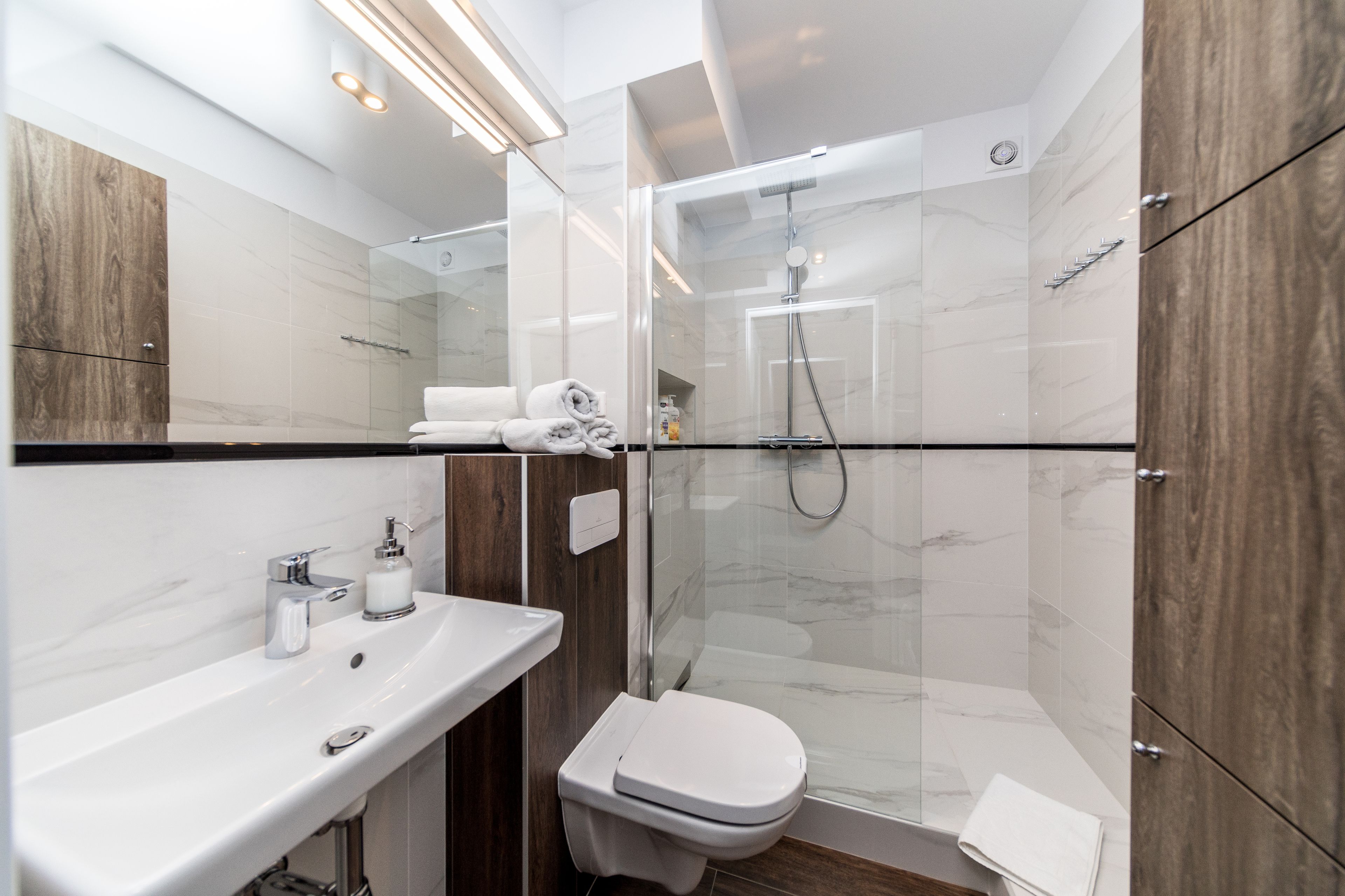 A modern bathroom with a glass-enclosed shower, a white sink, and a toilet.