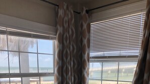 Un dormitorio con cama, lámpara y vista al mar a través de la ventana.