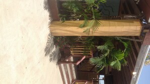 Una estructura de madera con una escalera que lleva a una puerta, rodeada de palmeras y un piso de concreto.