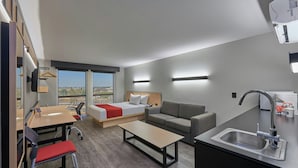 A modern hotel room with a bed, sofa, dining table, and kitchenette. - City Express by Marriott Salamanca (Salamanca)