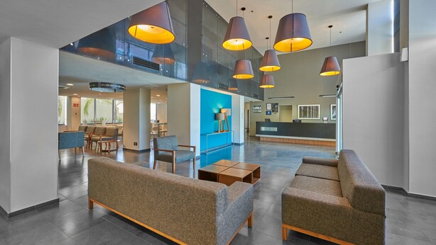 A spacious lobby with modern furniture, a reception desk, and a view of the interior. - City Express by Marriott Salamanca (Salamanca)