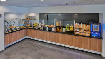 A buffet area with various food stations, a coffee machine, and a juice dispenser.