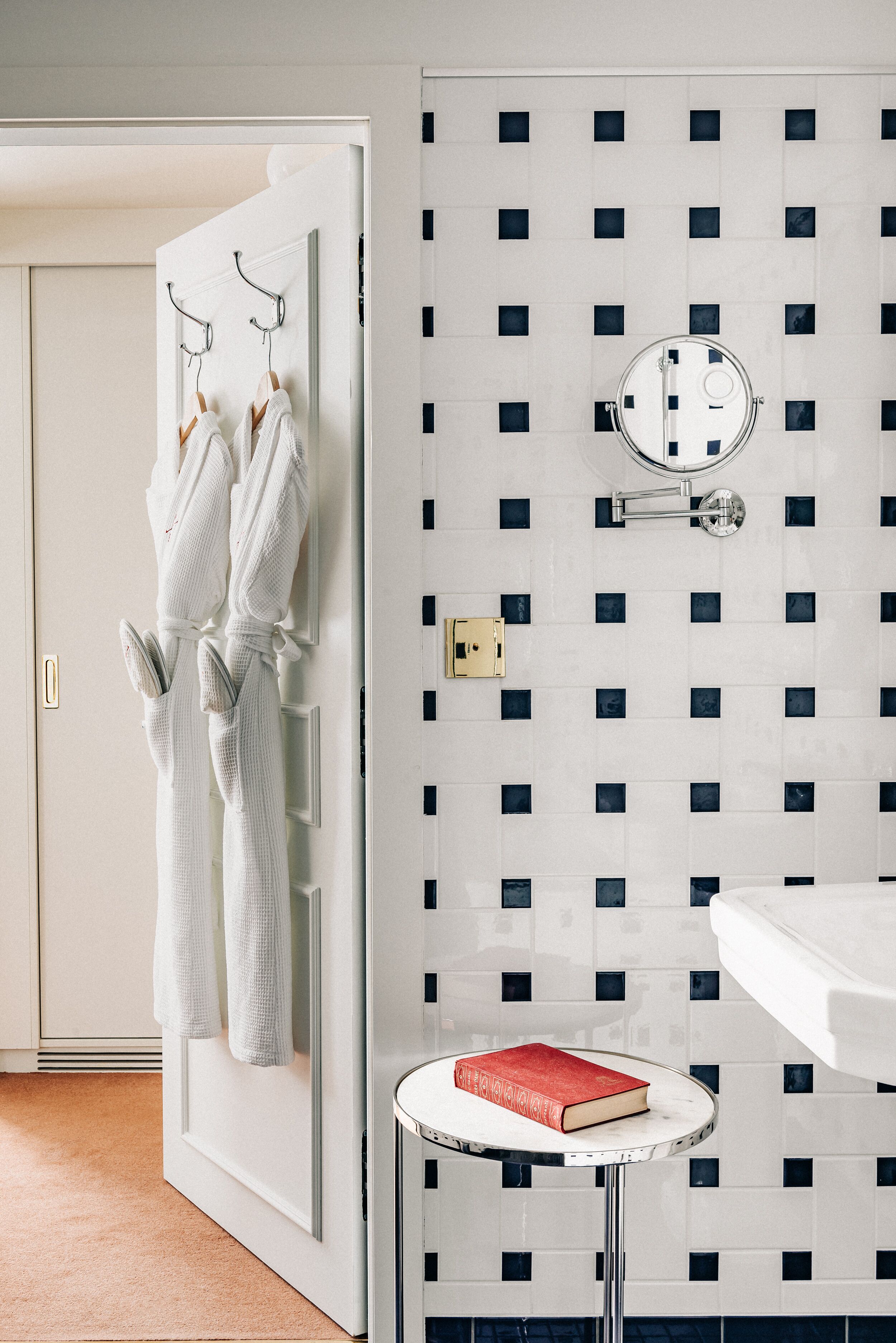 Un bagno con un lavandino bianco, uno specchio e un portascopevoli con due accappatoi bianchi.