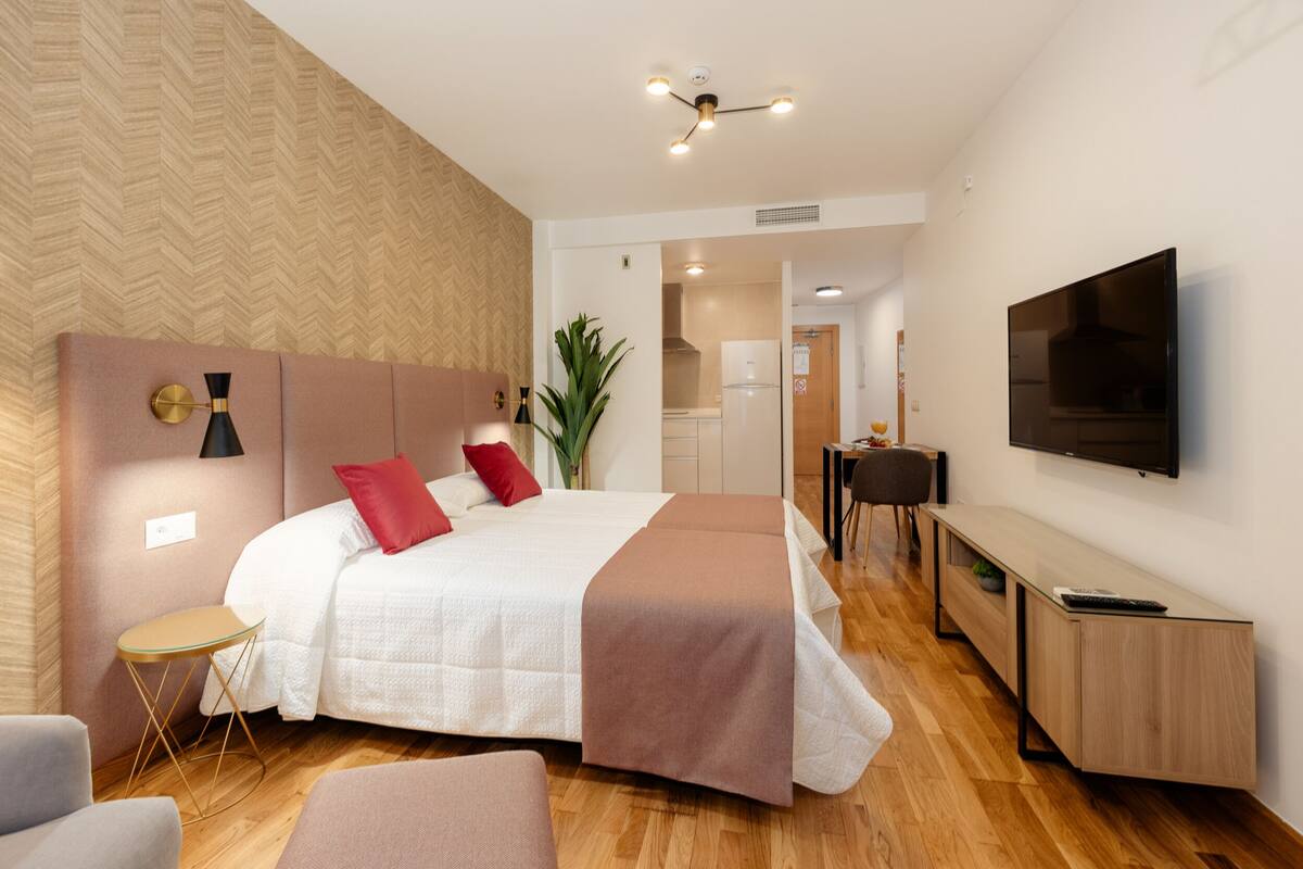 Een moderne hotelkamer met een groot bed, nachtkastjes, een televisie en een bureau.