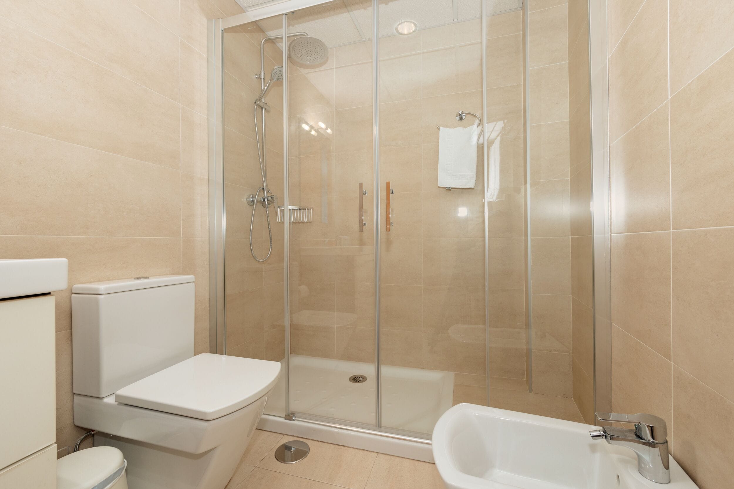 A modern bathroom with a glass-enclosed shower, a toilet, and a bathtub.