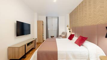 A modern hotel room with a large bed, a flat-screen TV, a wooden console table, and a view of the city through a window.