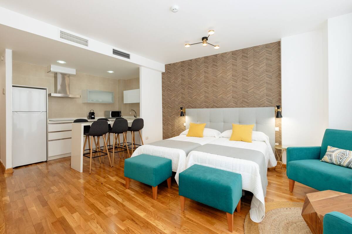 Een moderne hotelkamer met twee bedden, een kitchenette en een eethoek.