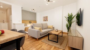A modern living room with a sofa, coffee table, and a dining area with chairs. - Debambú (Málaga)