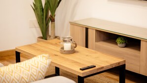 A wooden table with a candle holder, a remote control, and a patterned cushion. - Debambú (Málaga)