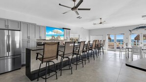 A modern kitchen with a central island, stainless steel appliances, and a large window overlooking the beach. - 1 Island Hideaway in the Keys (Marathon)