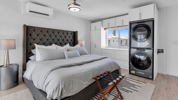 A bedroom with a large bed, a ceiling fan, an air conditioner, and a washing machine. - 1 Island Hideaway in the Keys (Marathon)