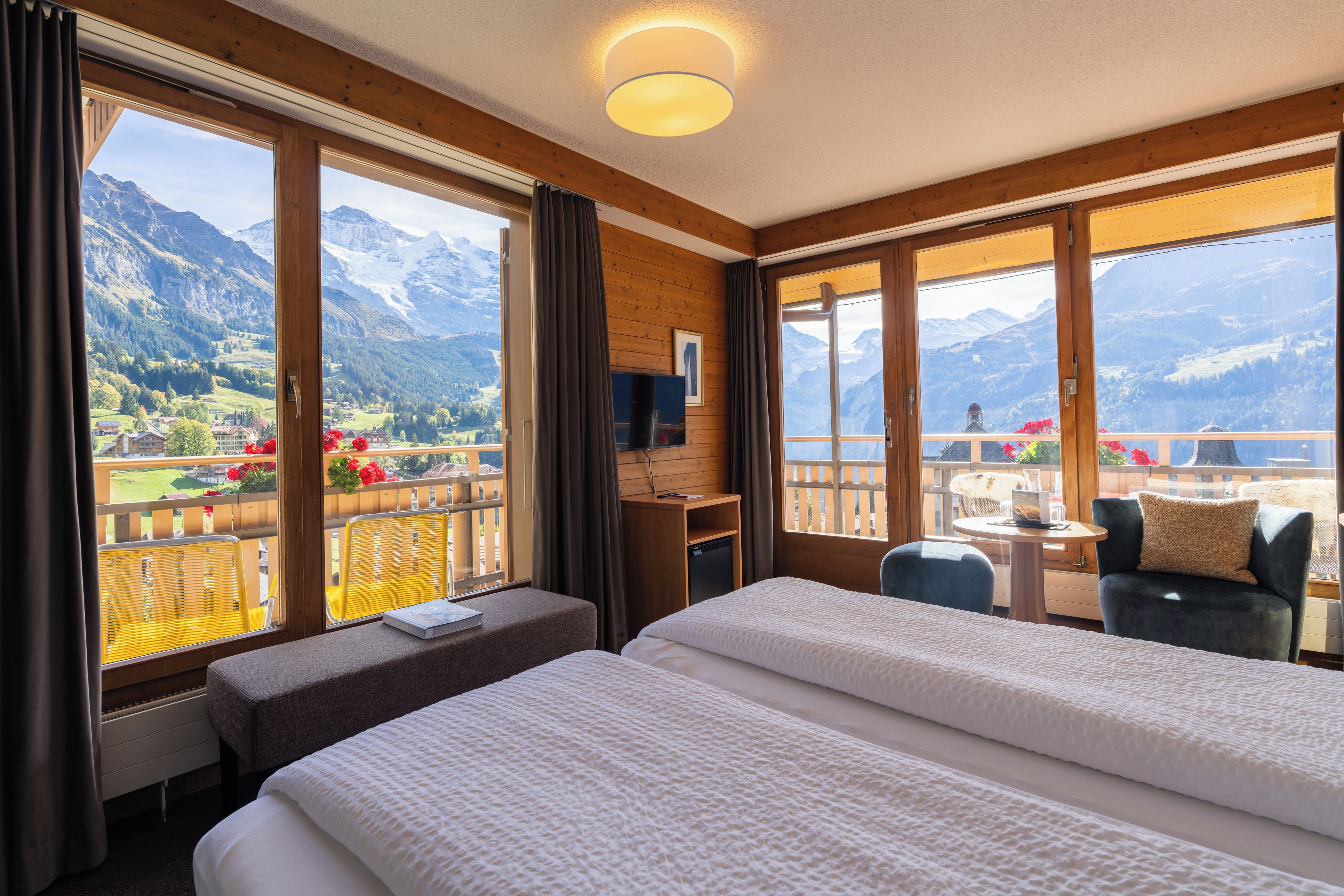 Ein Hotelzimmer mit Bett, Schreibtisch, Stuhl und einem Balkon mit Bergblick.