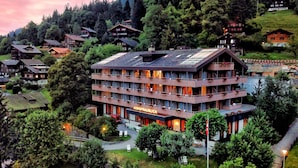 Een meerlaags hotel met balkons, omringd door bomen en andere gebouwen.