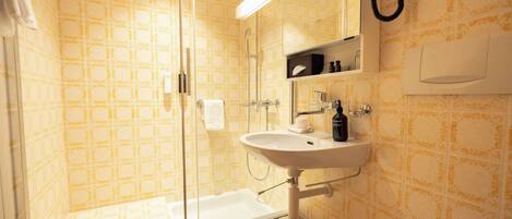 A bathroom with a shower, a sink, a mirror, and a toilet.