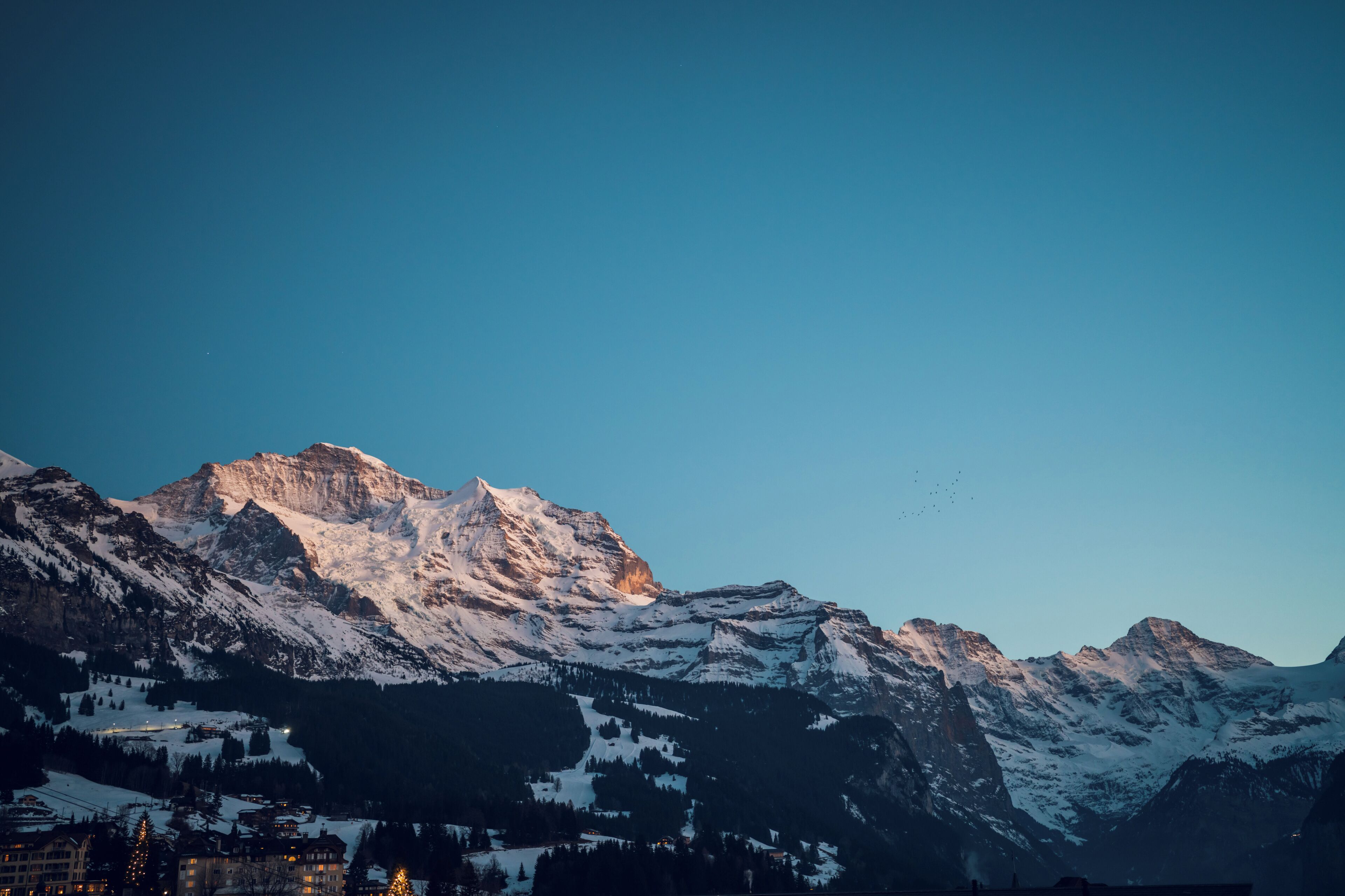 A mountain landscape with snow-covered peaks and a town below.