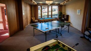 A room with two ping pong tables, a foosball table, and a billiards table.