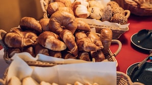 Een tafel met diverse gebakken producten, waaronder brood en gebak, gerangschikt in manden.