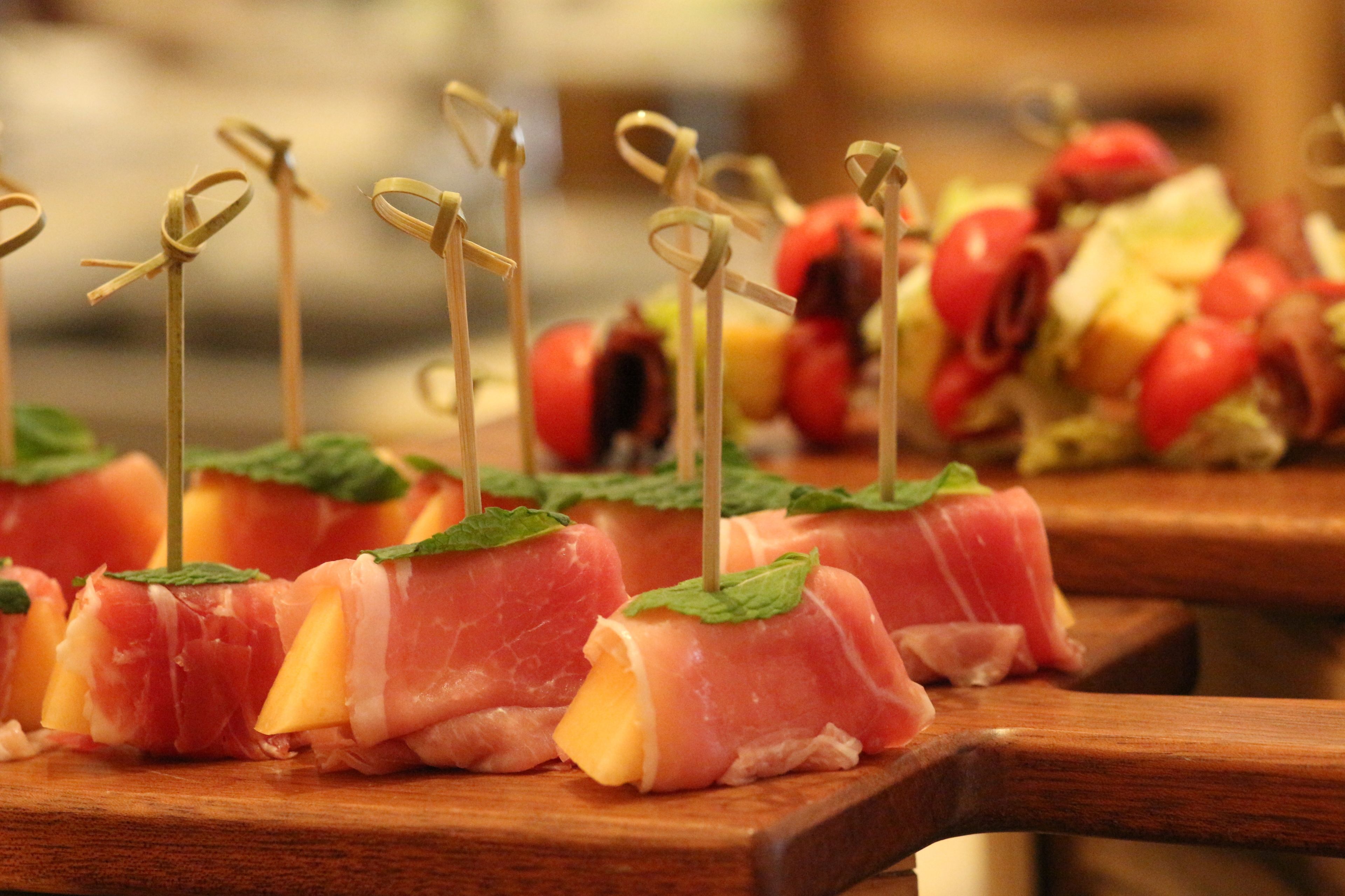 A wooden board with food items, including meat and cheese, garnished with mint leaves.