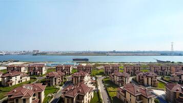 A residential area with modern apartment buildings, a body of water, and a distant city skyline.