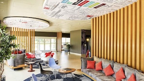 A modern lobby with a curved sofa, red cushions, a coffee table, and a large plant. - ibis Rio Branco (Rio Branco)