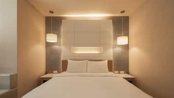 A hotel room with a large bed, two bedside tables, and a headboard with integrated lighting.