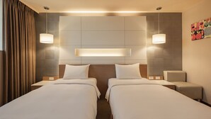 A hotel room with two beds, a headboard, bedside tables, and wall-mounted lamps. - Kindness Hotel Sanduo Shopping District (Kaohsiung)