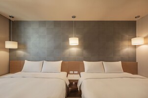 Una camera d'albergo con due letti, una testiera in legno e lampade a parete.