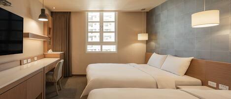 A hotel room with two beds, a desk, a chair, a TV, and a window with a view of buildings.