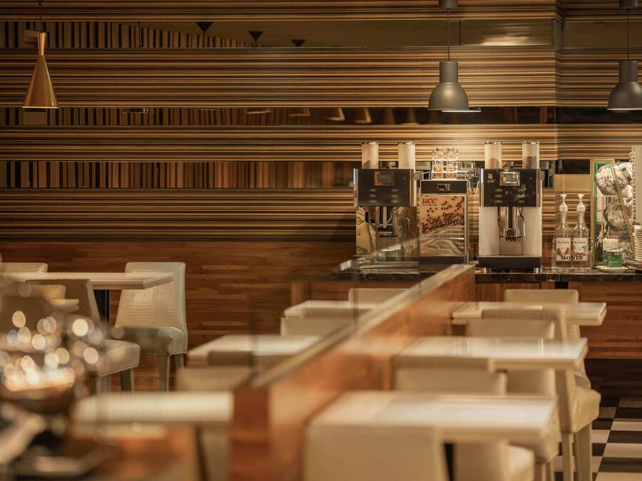 A modern restaurant with a wooden wall design, a coffee machine, and seating arrangements.