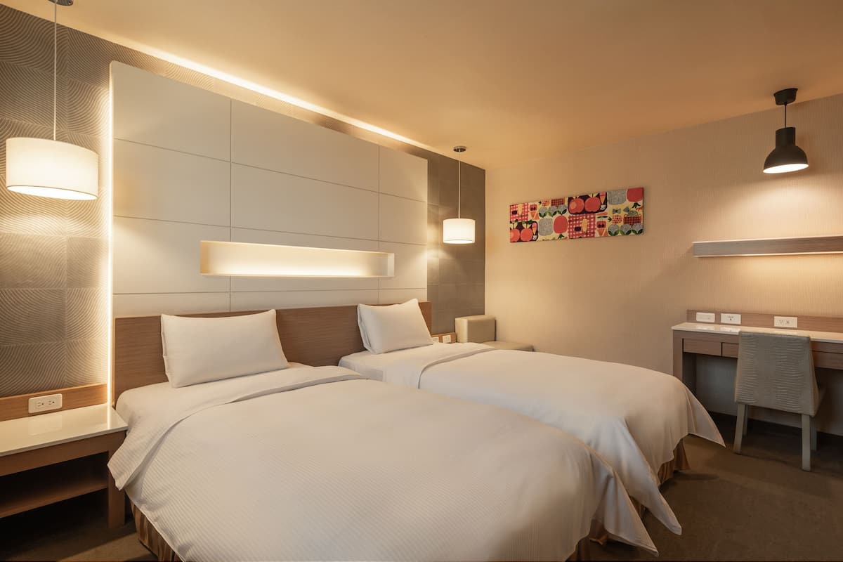 A modern hotel room with two beds, a desk, and a wall-mounted artwork.