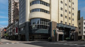 Un edificio moderno con fachada curva, ventanas amplias y acceso a nivel de calle.