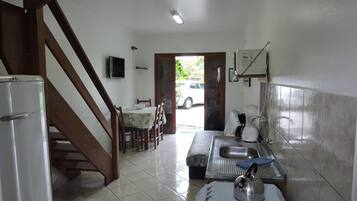 Una cocina equipada con refrigerador, estufa, pileta y un comedor con mesa y sillas.