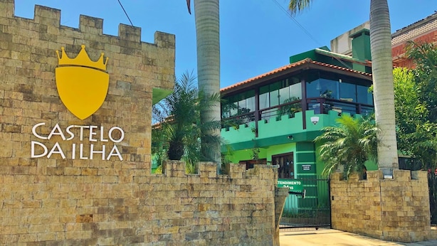 Una entrada con temática de castillo, con un muro de piedra y un edificio verde al fondo.