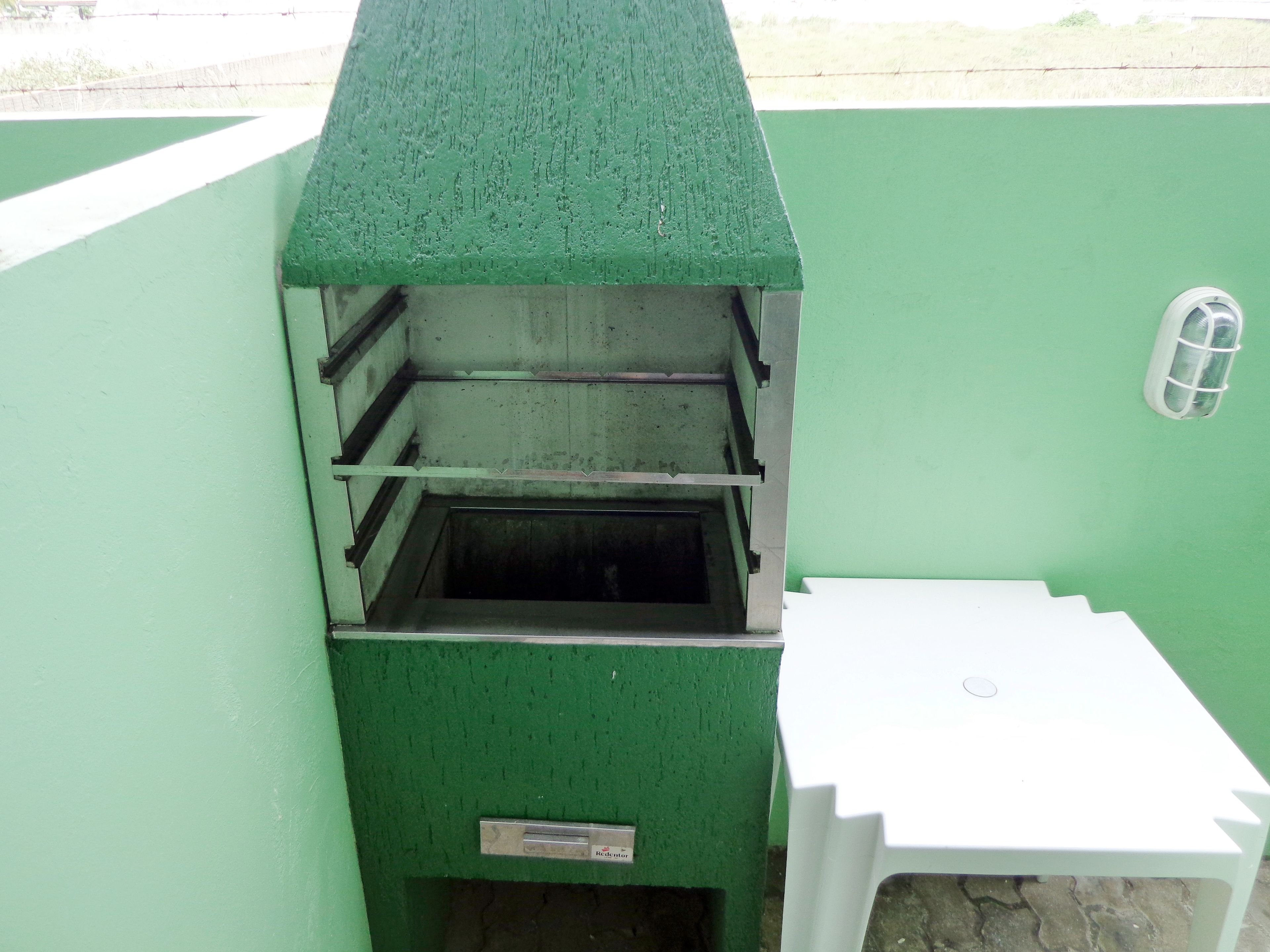 A green outdoor grill with a white table beside it.