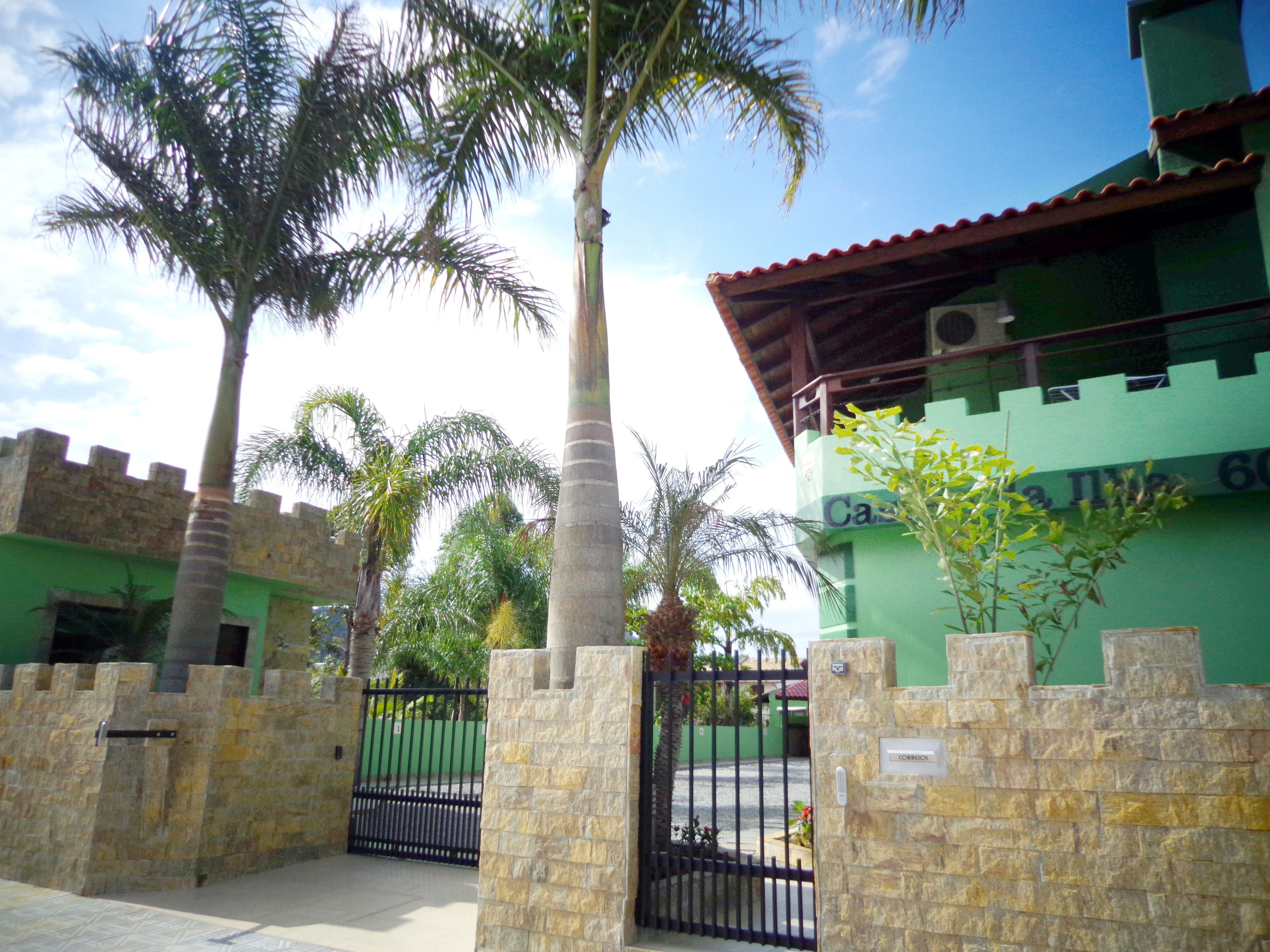 A building with a green facade, a stone wall, and a black gate.